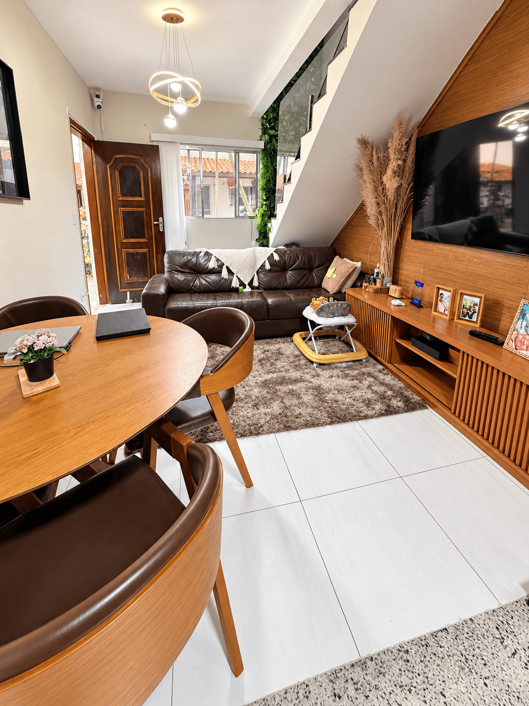 Sala de estar com mesa de jantar e escada do sobrado